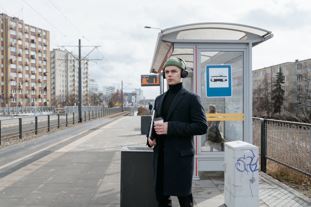 A Man Wearing a Black Coat with a Knit Cap Standing on a Train Station